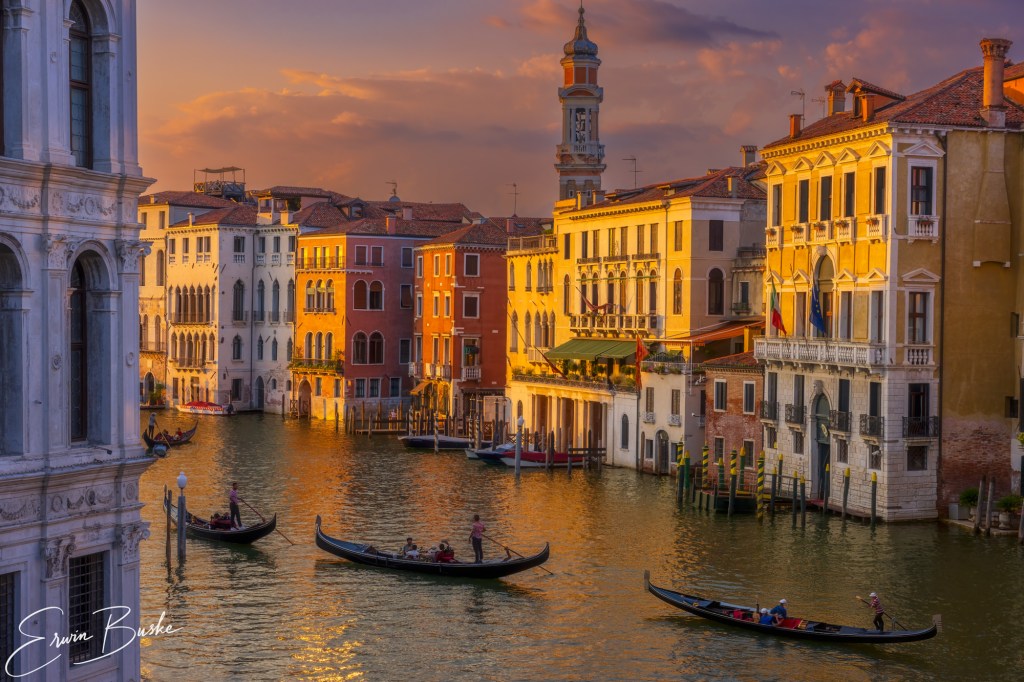 Venice gondolas silhouetted against warm sunset light on the lagoon.